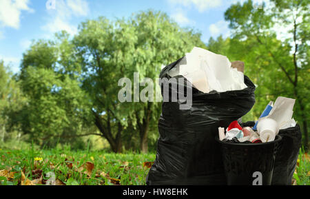 Full black wastebasket and plastic bags outside Stock Photo