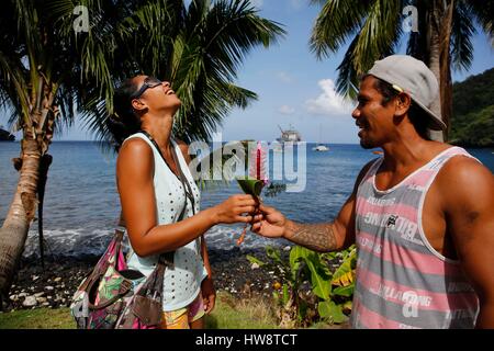 France, French Polynesia, Aranui 5 freighter and passenger ship cruise to the Marquesas islands archipelago, Tahoata island, village of Vaitahu, man offering a flower to a laughing lady Stock Photo