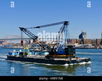 Commercial barge with crane, light blue trim, heading down the East River, New York, New York, USA Stock Photo