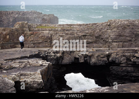 Boy walks along the rock at the Bridges of Ross in Ireland Stock Photo