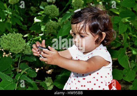 Baby girl 3 years old trying to shoot a photo camera with funny expressions Stock Photo