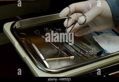 Dentist's tools / Dentist holds one of his instruments from a tray of dentist's tools. Stock Photo