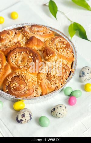 Easter pastry. Fresh Homemade Creamy Cinnamon Buns with Nuts. Cinnamon Rolls with Cream Cheese for Easter Breakfast with Easter decoration close up. Stock Photo