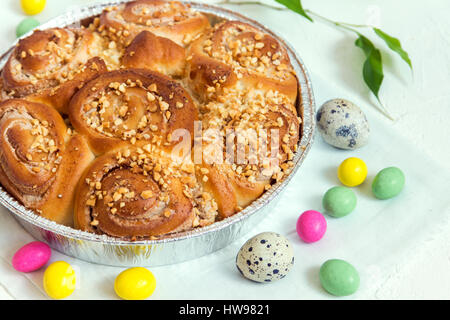 Easter pastry. Fresh Homemade Creamy Cinnamon Buns with Nuts. Cinnamon Rolls with Cream Cheese for Easter Breakfast with Easter decoration close up. Stock Photo