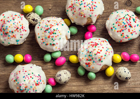 Easter pastry. Fresh Homemade Carrot Mini Cakes with White Creamy Sugar Icing and Colorful Decor over wooden background with copy space. Easter Cakes  Stock Photo