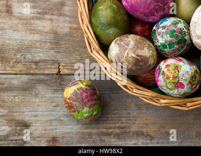 Group of colorful Easter eggs decorated with flowers made by decoupage technique, in a basket on wooden background/ top view Stock Photo