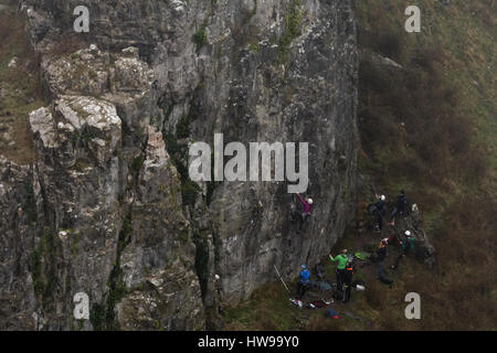 Group of rock climbers in fog at Cheddar Gorge ascend cliff in Somerset, UK, in one of Britain's most impressive areas of natural beauty Stock Photo