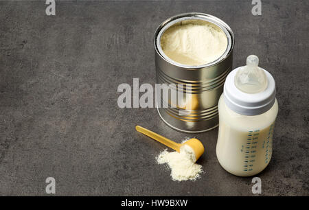 Baby bottle and milk powder on dark grey table Stock Photo