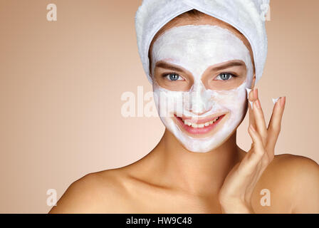 Young woman applying moisturizer cream on her face. Photo of smiling woman receiving spa treatments. Grooming himself Stock Photo
