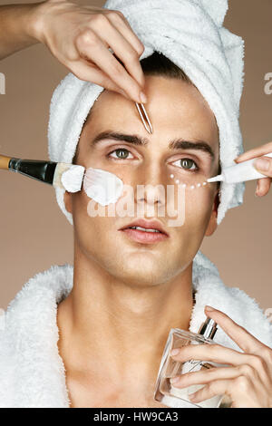 Young man and many hands making different beauty salon services(beautician and stylist). Grooming himself Stock Photo