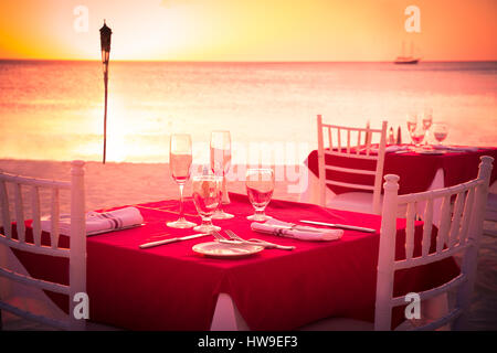 Table on beach set for romantic sunset dinner Stock Photo