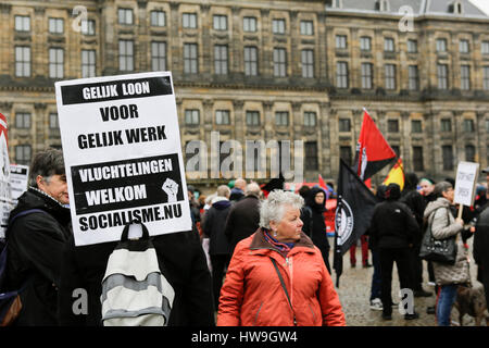 Amsterdam, Netherlands. 18th Mar, 2017. An activist holds a sign that reads 'Equal pay for equal work - refugees welcome' outside the Royal Palace. Around 2,000 people marched through Amsterdam, to protest against racism and discrimination. The protest was part of an European wide day of protest against the EU Turkey Refugee Deal and the International Day for the Elimination of Racial Discrimination (21. March). Credit: Michael Debets/Pacific Press/Alamy Live News Stock Photo