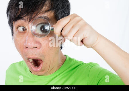 Asian Chinese Man Looking through a Magnifying Glass in isolated White Background Stock Photo