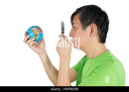 Asian Chinese Man Looking At Globe Through Magnifying Glass in isolated White Background Stock Photo