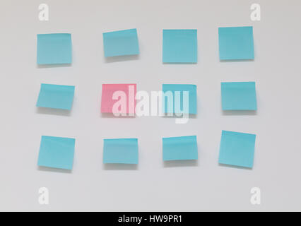 Single pink post it note in sea of blue post it notes Stock Photo