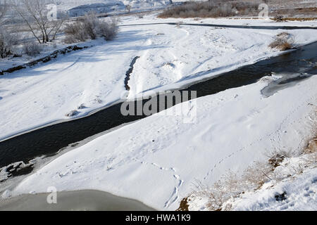 Ice-free mountain river in winter with animal trails near Sarykum barchan. Dagestan, Russia Stock Photo
