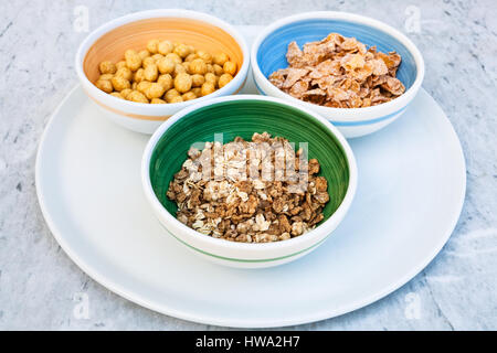 three bowls with cold breakfast cereals on white plate Stock Photo