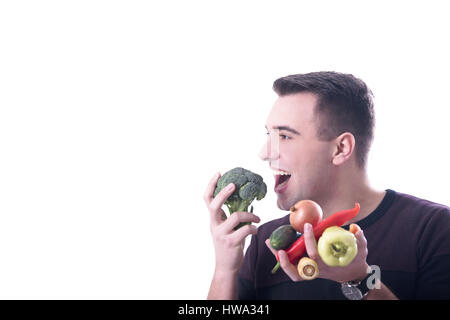 Young man eating vegetables on white background Stock Photo