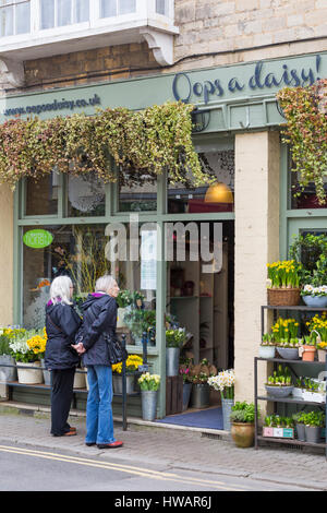 Oops a Daisy florist shop in Cirencester full of Spring flowers, ideal for Mothers Day, as couple of women look in window at Cirencester in March Stock Photo
