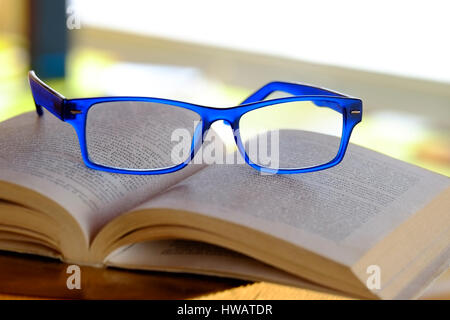 Blue Glasses Resting on Stack of Books and Magazines Stock Photo