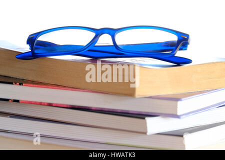 Blue Glasses Resting on Stack of Books and Magazines Stock Photo