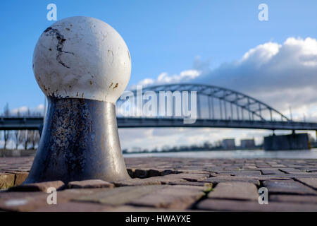 old bollard on the cobbled quay with a steel arch bridge in the background Stock Photo