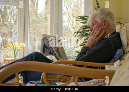 Elderly man reading newspaper Stock Photo