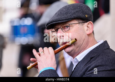 A man with a moustache, and wearing a tweed flat cap plays a traditional Irish wooden flute. Stock Photo