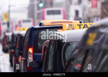 Black London-style taxis with yellow taxi roof signs lined up at a taxi rank outside Belfast City Hall Stock Photo