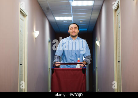 Young handsome pushing cleaning cart - a series of HOTEL images. Stock Photo