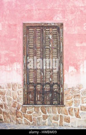 Brown wood window shutters on pink roughcast and stone wall in Mallorca, Spain. Stock Photo