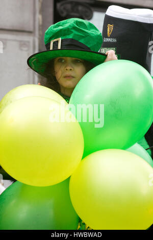 Little girl wearing a novelty Irish hat in amongst Balloons for the St Patricks day parade in London Stock Photo