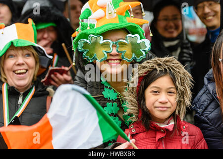 Belfast, Northern Ireland. 17 Mar 2016 - Tourists wear green, white and yellow hats, shamrocks and wave an Irish tricolour flag to celebrate Saint Patrick's Day. Stock Photo