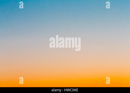 Colorful Natural Background Of Clear Sunny Sky At Sunset Or Sunrise. Yellow, Orange And Blue Colors. Combination Of Warm And Cool Cold Colors. Stock Photo