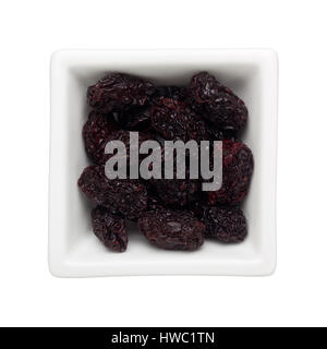 Dried black dates in a square bowl isolated on white background Stock Photo