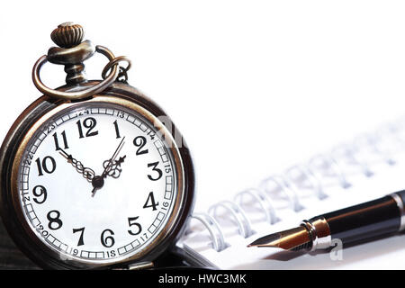 Fountain pen on spiral notebook near pocket watch with free space for text Stock Photo