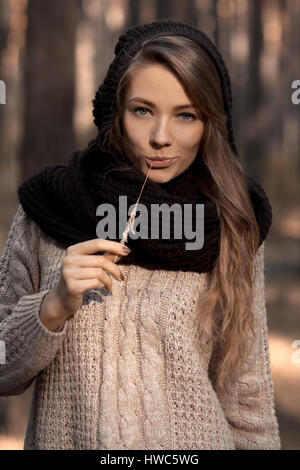 Close-up of fashionable model,glamorous girl in scarf and hat with straw in teeth,fingers,hands,mouth.Perfect sunny face with blue eyes.Sunny portrait Stock Photo