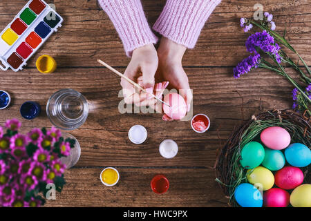Female hands painting Easter eggs on wooden table. Stock Photo