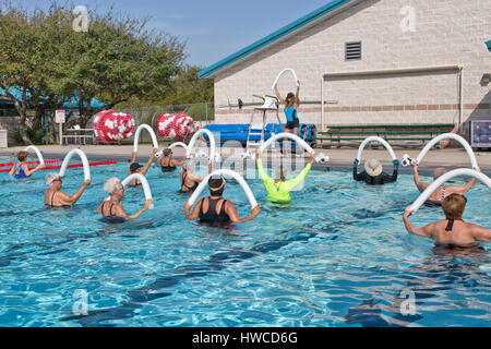 Group of women attending Water Aerobics class, Instructor demonstrating,  using  styrofoam 'water noodle', outdoor heated pool, Rockport, Texas. Stock Photo
