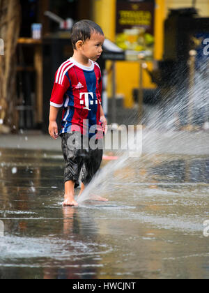Vertical portrait of a little boy playing in Fountain Square in Singapore. Stock Photo