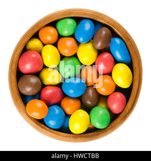Colorful chocolate peanut candies in wooden bowl over white. Peanuts coated in milk chocolate with candy shell in different colors.Macro photo. Stock Photo