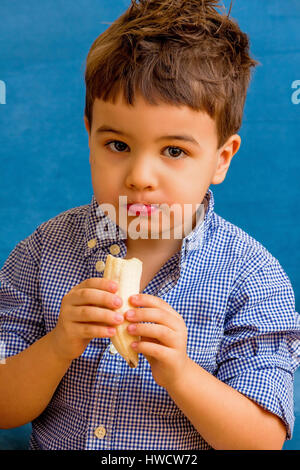 A small boy eats a banana. Symbolic photo for food, Ein kleiner Junge isst eine Banane. Symbolfoto für Ernährung Stock Photo