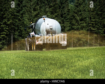 A farmer goes with liquid manure on a field for fertilising, Ein Bauer fährt mit Gülle auf einem Feld zum Düngen Stock Photo