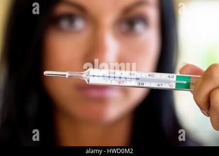 A woman holds a clinical thermometer Hinterhand. Symbolic photo for ill and fever, Eine Frau h‰lt eine Fieberthermometer Hinterhand. Symbolfoto f¸r kr Stock Photo