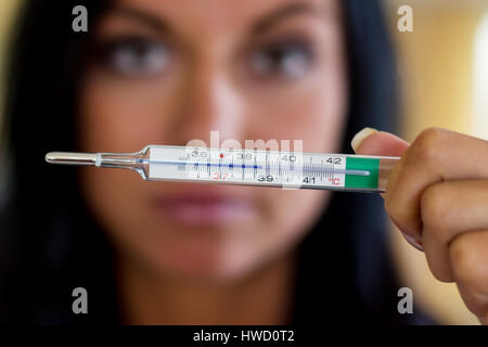 A woman holds a clinical thermometer Hinterhand. Symbolic photo for ill and fever, Eine Frau hält eine Fieberthermometer Hinterhand. Symbolfoto für kr Stock Photo