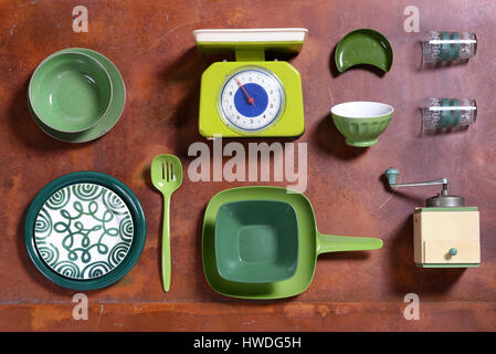 Assortment of green themed kitchen tools on a wooden table with a scale, grinder, bowls, plate and tray viewed from overhead in a cooking and catering Stock Photo