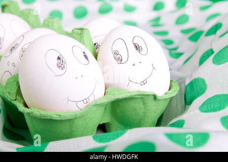 Easter eggs with funny faces in the green box on polka dot tablecloth. Emoji funny egg. Stock Photo