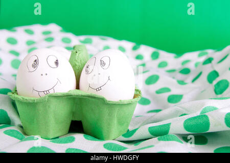 Easter eggs with funny faces in the green box on polka dot tablecloth. Emoji funny egg. Stock Photo