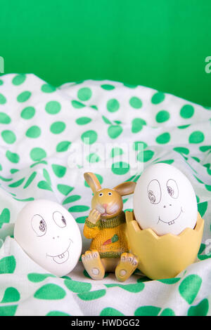 Easter eggs with funny faces near bunny on polka dot tablecloth. Emoji funny egg. Stock Photo