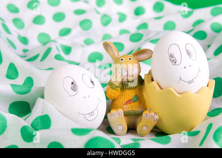 Easter eggs with funny faces near bunny on polka dot tablecloth. Emoji funny egg. Stock Photo